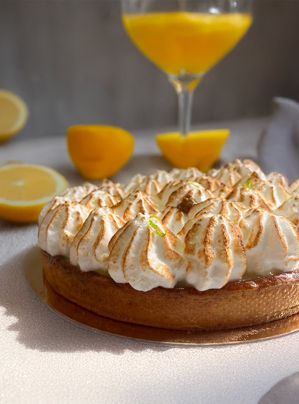 Tarte citron meringuée de Sheli Pâtisserie sur fond ensoleillé avec citron frais en arrière-plan